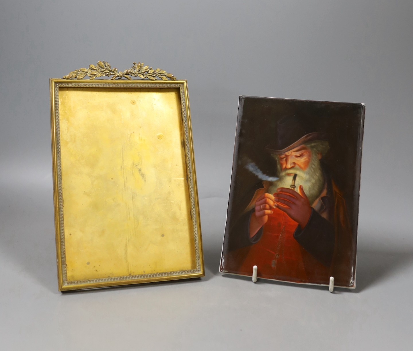 A KPM-style painted porcelain plaque entitled verso, “Der Raucher nach Hom”, in cast brass frame